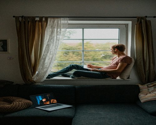 Person taking a short break from laptop to look out the window